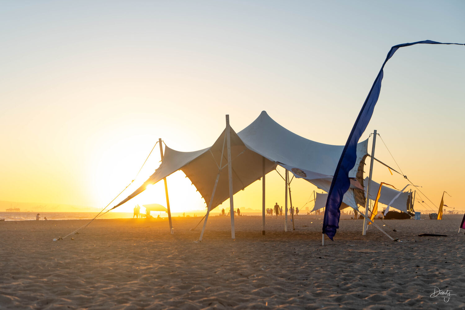 A stretch tent on the beach at sunset