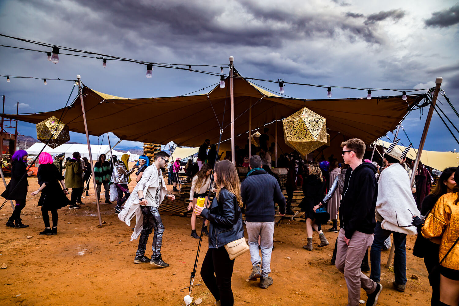 A crowd dancing under a stretch tent strung with lights