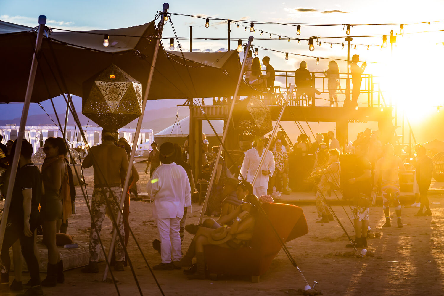 A crowd under a dark stretch tent at dusk