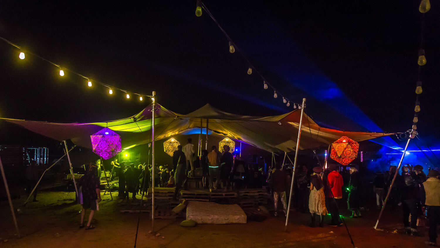 Linked stretch tents lit at night under festoon lights