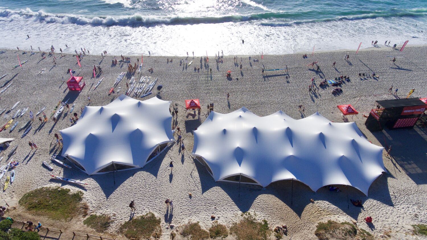 Top-down view of white stretch tents on the sand