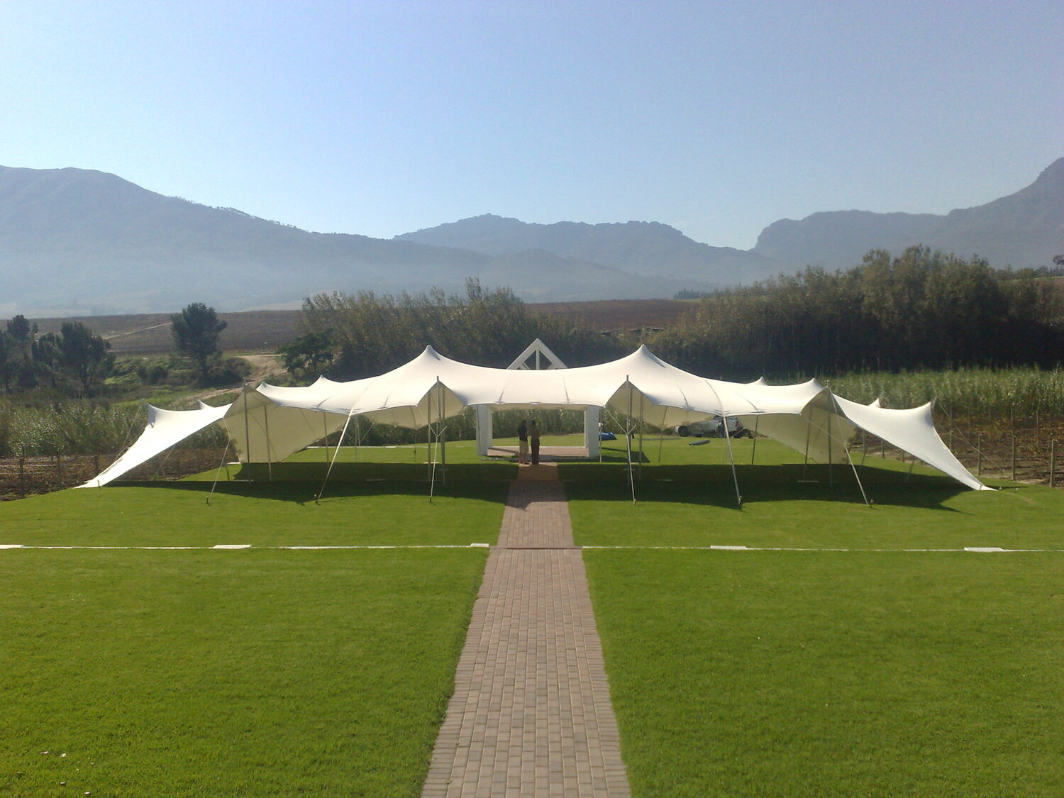 A large white stretch tent on a lawn with mountains behind