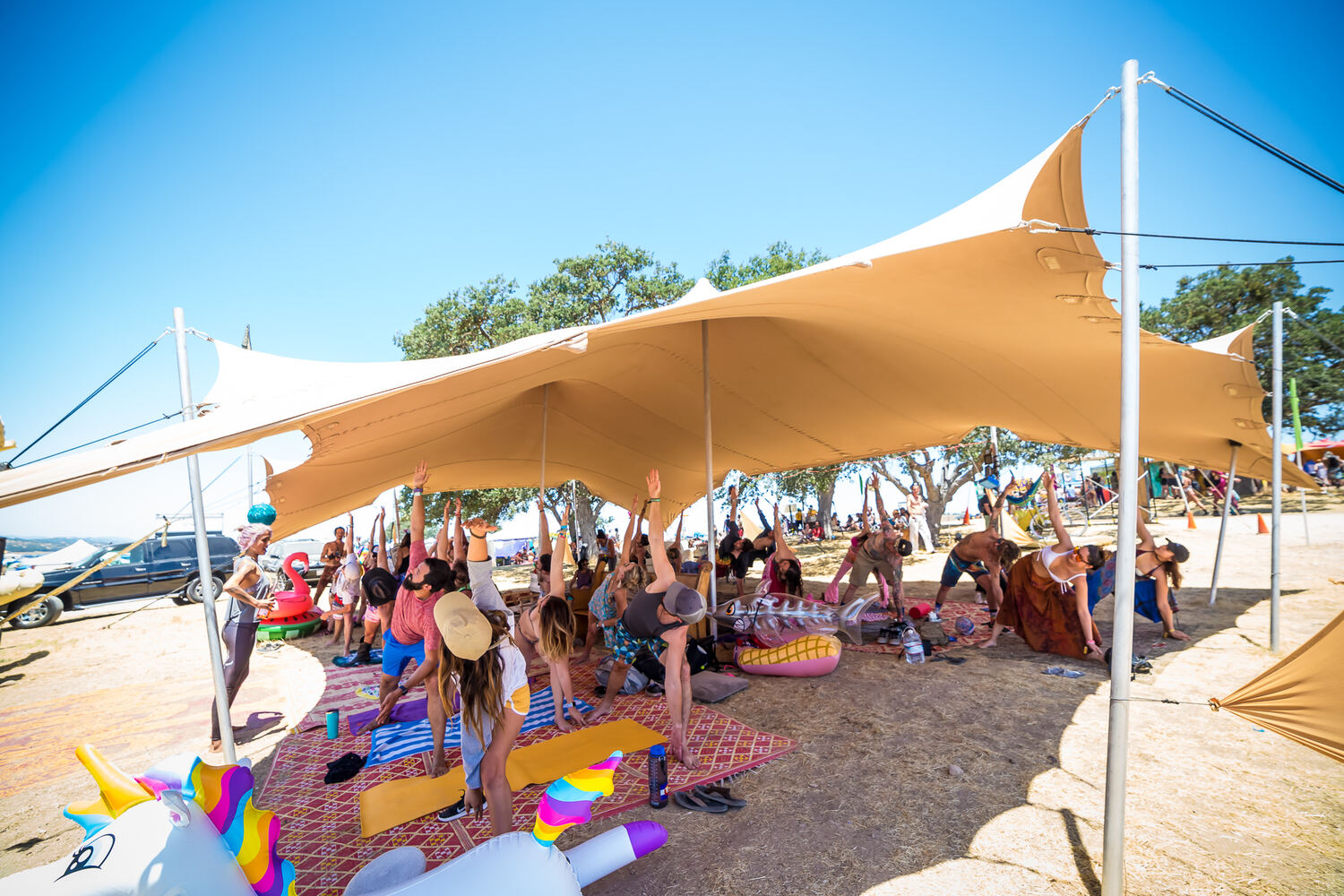 People resting in the shade of a tan stretch tent
