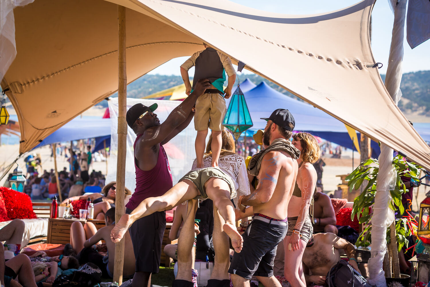 A crowd gathered under a tan stretch tent
