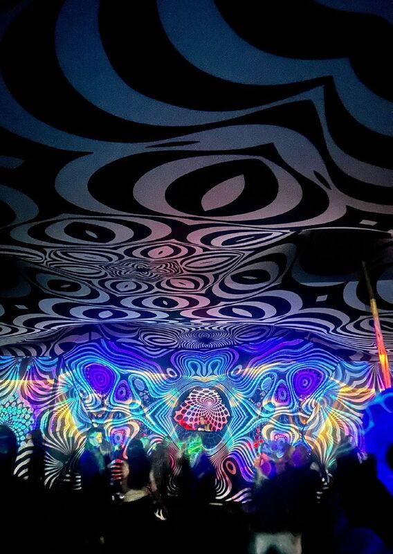 A black and white swirl print glowing over a dance floor