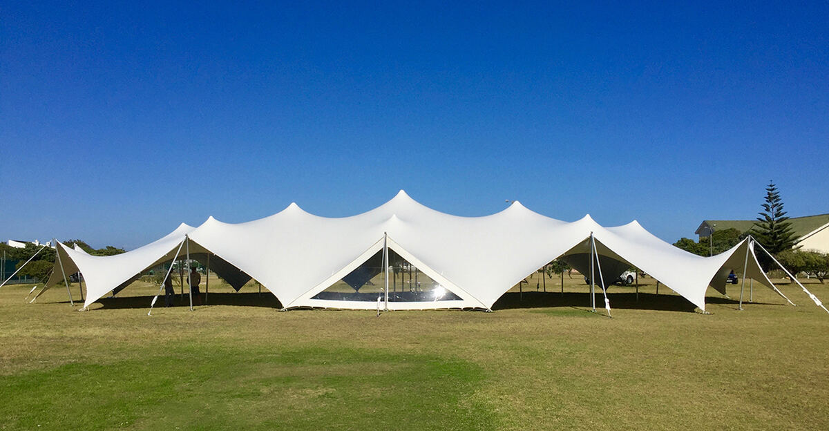 A row of linked white modular stretch tents on a lawn